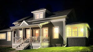 A two-story house with a front porch, a covered entryway, and a well-lit exterior. - Stylish Historic Home – Timeless Charm with Modern Touches (Bovina Center)