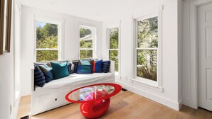 A bright room with a white bench against a wall, large windows, and a red table. - Brookview Farm Country Living (Modena)