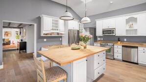 A modern kitchen with white cabinets, a wooden island, stainless steel appliances, and pendant lighting. - Brookview Farm Country Living (Modena)
