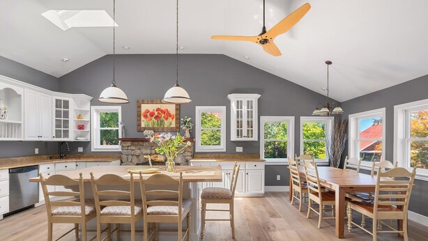 A spacious kitchen with wooden cabinets, a central island, and a dining area with wooden chairs. - Brookview Farm Country Living (Modena)