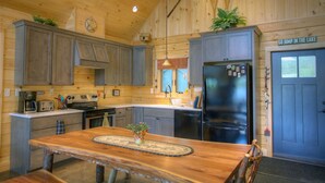 Una cocina rústica de estilo cabaña con armarios de madera, una isla central y un refrigerador.
