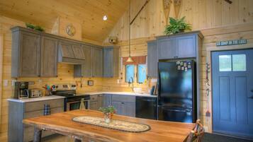 A rustic cabin-style kitchen with wooden cabinets, a central island, and a refrigerator.