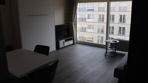 Une chambre d’hôtel moderne dotée d’une grande fenêtre, d’un téléviseur à écran plat, d’une table à manger et d’un canapé.