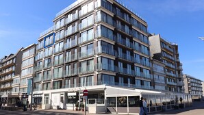 Un hôtel à plusieurs étages doté de balcons, d’un café et d’une devanture visible depuis la rue.