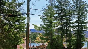 Une route bordée d’arbres, avec un panneau indiquant « INTERDICTION DE STATIONNER » d’un côté, et d’où l’on aperçoit un lac et des montagnes au loin.
