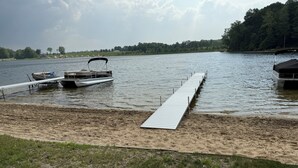 A lake with a dock extending into the water, surrounded by grassy areas and trees. - Charming Lakefront Retreat with Sandy Beach – Perfect Getaway  (Shelbyville)