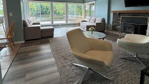 A modern living room with a sectional sofa, a white armchair, and a fireplace. - Charming Lakefront Retreat with Sandy Beach – Perfect Getaway  (Shelbyville)