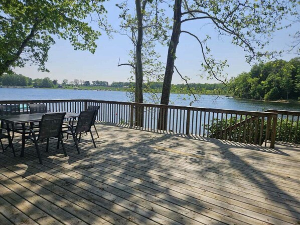 Une terrasse en bois avec une table et des chaises donnant sur un lac.