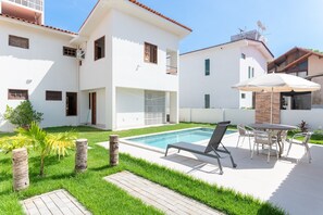 Une maison moderne à deux étages, dotée d’une piscine, d’un espace de détente extérieur et d’un jardin bien entretenu.