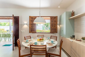 Un espace repas comprenant une table ronde, des chaises et un luminaire suspendu.