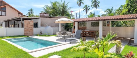 A backyard with a swimming pool, outdoor furniture, and a covered patio area.