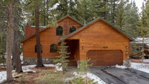 A log cabin with a stone foundation, a garage, and a driveway.