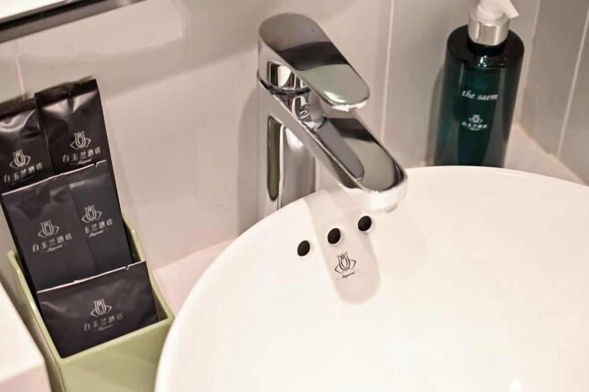 A bathroom with a white sink, a chrome faucet, and a green soap dispenser.