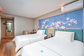 A hotel room with two beds, a large floral artwork on the wall, a small table with a chair, and an air conditioning unit. - Baiyulan Hotel (Shenzhen Railway Station & Laojie Metro Station Branch) (Shenzhen)