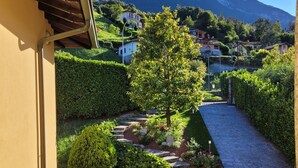 Un sentier de jardin qui mène à un point de vue sur la montagne, avec des haies soigneusement taillées et un chemin de pierres.