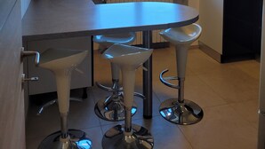 Une cuisine moderne dotée d’une grande fenêtre, d’une table à manger et de deux tabourets de bar.