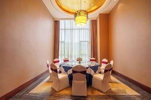 A conference room with a round table, white chairs, and a chandelier. - Kailong Holiday Hotel (Longling)