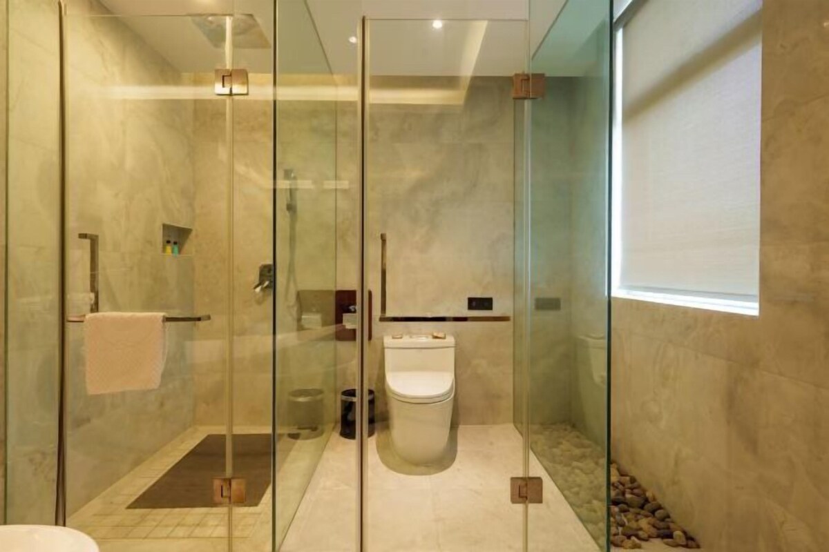 A modern bathroom with a glass-enclosed shower, a toilet, and a sink.