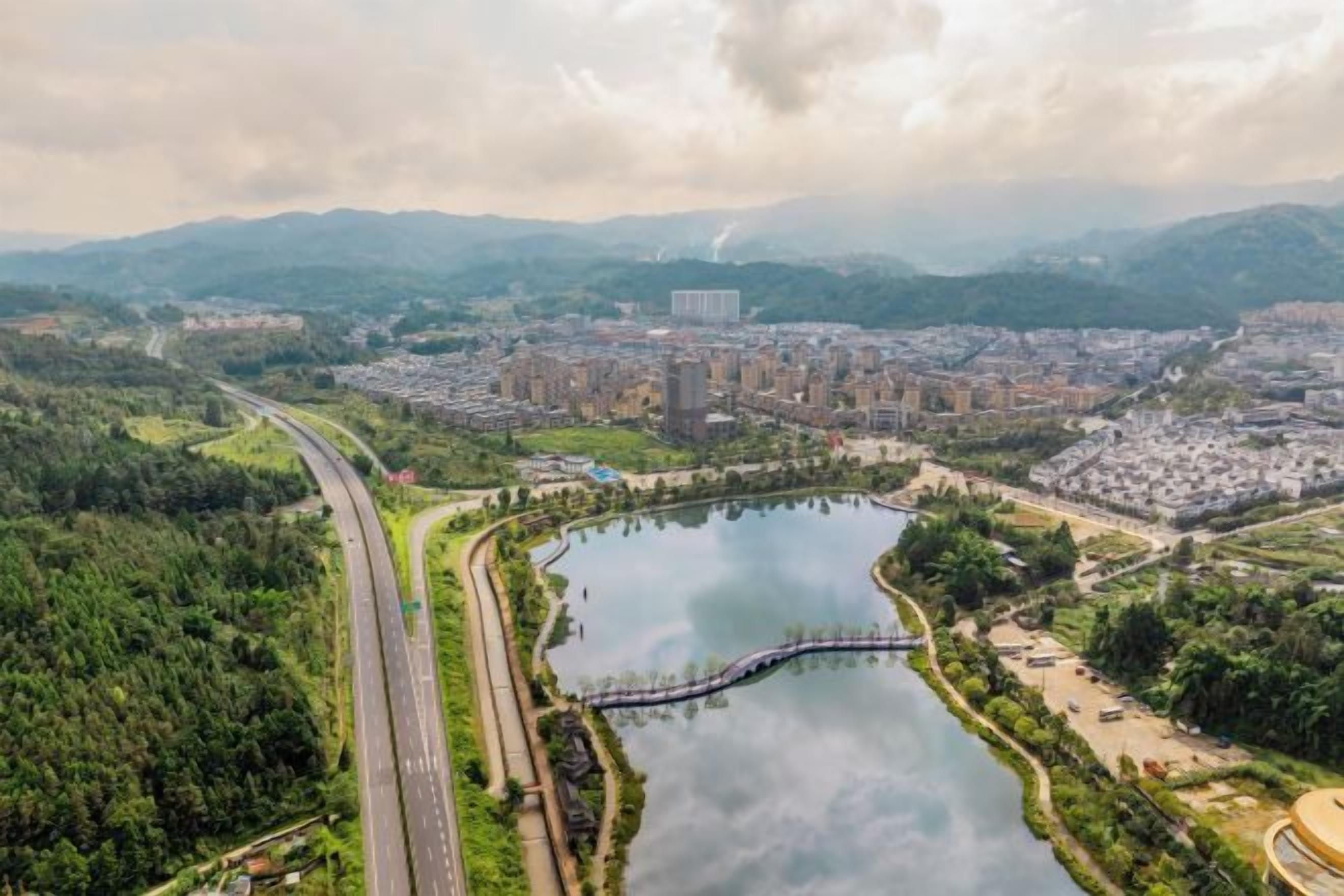 An aerial view of a city with a river, a bridge, and a highway.