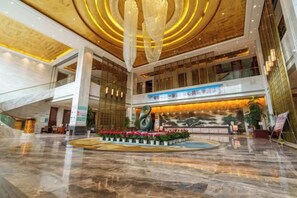 A spacious lobby with a marble floor, a central reception desk, and a large chandelier. - Kailong Holiday Hotel (Longling)