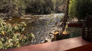 Une terrasse en bois donnant sur une rivière, avec des arbres et un ciel dégagé.