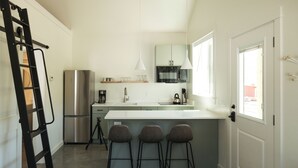 A compact kitchen with a central island, bar stools, a stainless steel refrigerator, and a microwave. - Farm stay near Yellowstone, Livingston, Bozeman, hiking, fishing, skiing (Livingston)