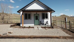 A small, single-story building with a green door and two windows, surrounded by a gravel driveway and a wooden fence. - Farm stay near Yellowstone, Livingston, Bozeman, hiking, fishing, skiing (Livingston)