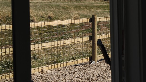 A view through a window of a mountainous landscape with a fence and a wooden post. - Farm stay near Yellowstone, Livingston, Bozeman, hiking, fishing, skiing (Livingston)