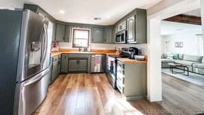 Une cuisine moderne avec des meubles gris, des appareils électroménagers en acier inoxydable et un plancher en bois.
