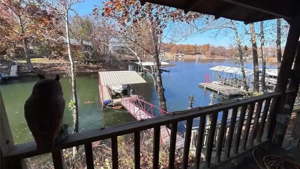 Une vue depuis un balcon abrité donnant sur un lac, avec des quais et des bateaux, le tout entouré d’arbres aux feuilles d’automne.