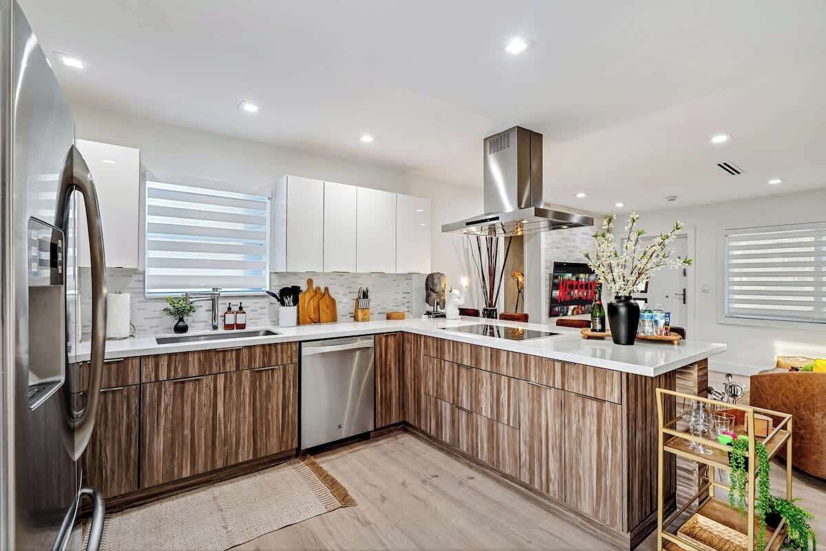 A modern kitchen with wooden cabinets, a stainless steel refrigerator, and a built-in dishwasher.