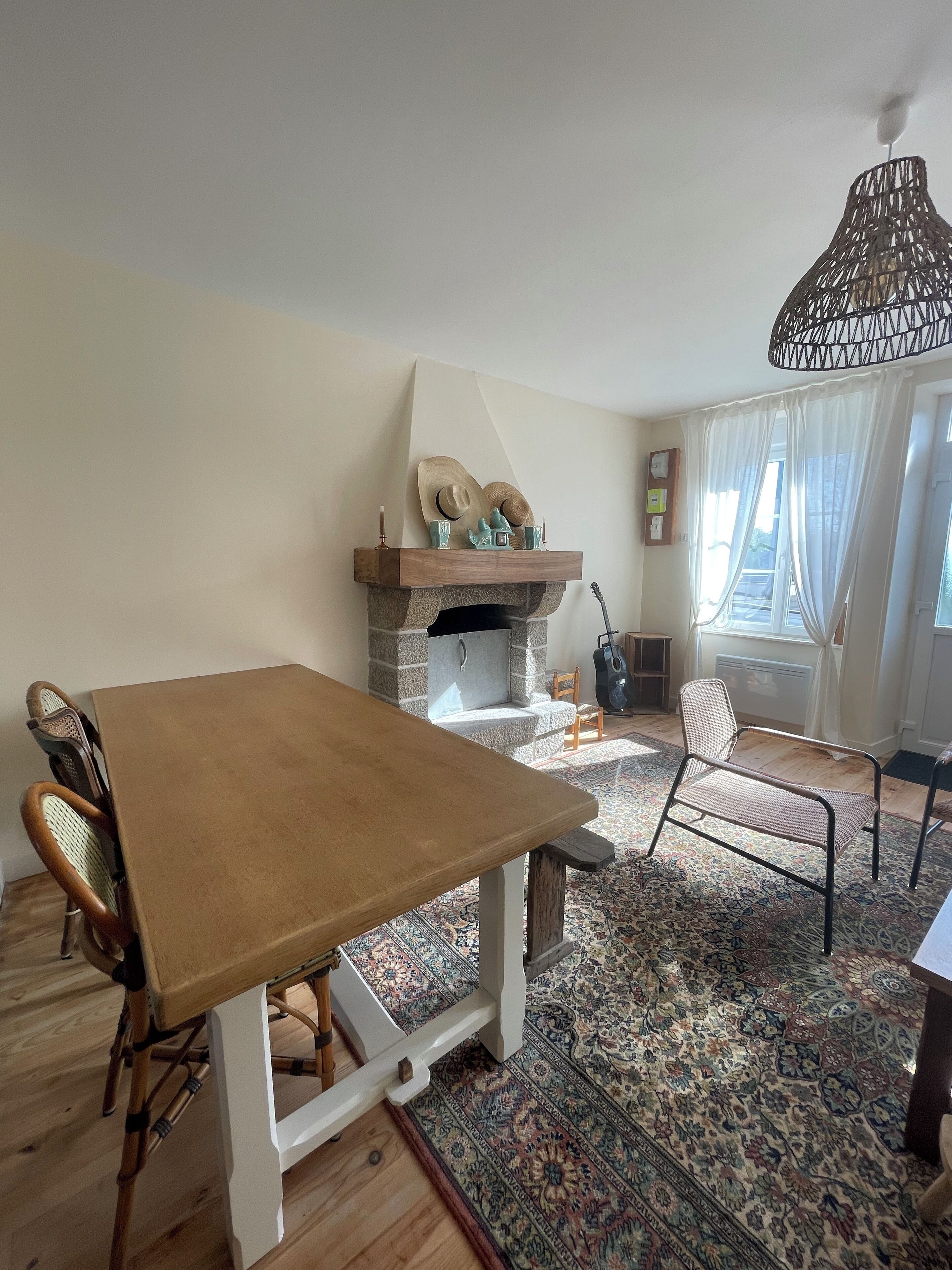A dining area with a wooden table and chairs, a stone fireplace, and a patterned rug.