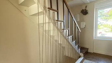 A staircase with wooden steps and a white handrail, leading to a landing with a white wall and a window.