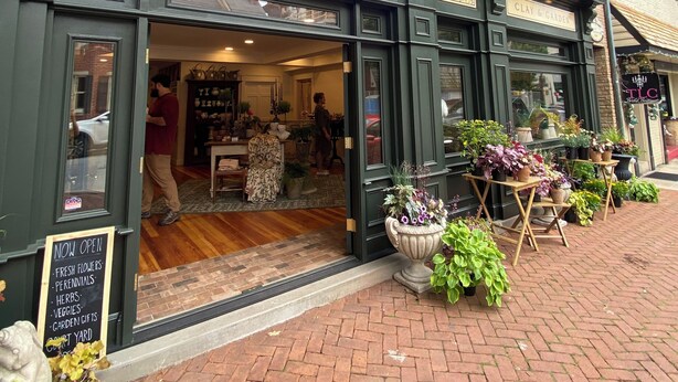 Une devanture de magasin avec une enseigne indiquant « PERENNIAL » et « CLAY & GARDEN ».