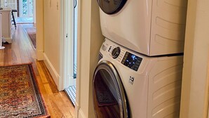 Un espace buanderie équipé d’un lave-linge et d’un sèche-linge à chargement frontal, doté d’un plancher en bois et agrémenté d’un tapis.