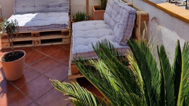A terrace with a white umbrella, a cushioned bench, and a potted plant. - Calafell Beachfront Escape. Spacious Attic with Rooftop Terrace and Pool. (CT)