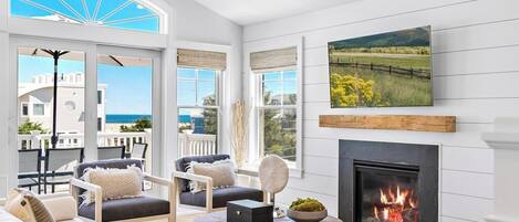Un salón espacioso con chimenea, asientos cómodos y grandes ventanales con vistas al exterior.
