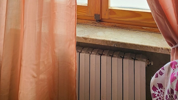 A window with orange curtains, a wooden door with a brass handle, and a radiator below. - B&B Ma Maison Govone  (Govone)