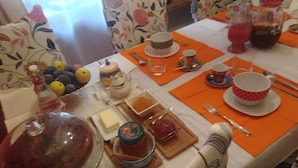 A dining table set with orange placemats, various dishes, and tableware. - B&B Ma Maison Govone  (Govone)