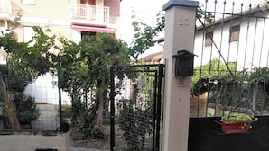A gated entrance with a metal gate, a trash bin, and a potted plant. - B&B Ma Maison Govone  (Govone)