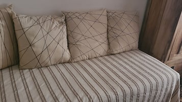 Un canapé beige recouvert d’un tissu à rayures, agrémenté de coussins aux motifs géométriques.