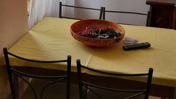 A dining area with a table set for two, featuring a decorative bowl and a remote control.
