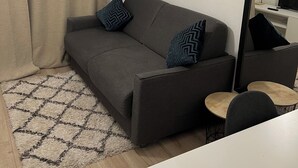A modern living room with a grey sofa, patterned rug, and a small round table.