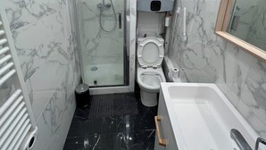 A compact bathroom with a glass-enclosed shower, a toilet, and a bathtub.