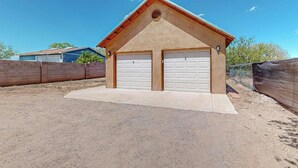 A single-story building with two garage doors, a sloped roof, and a brick wall in the background.