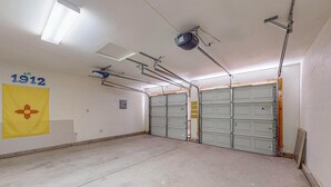 A garage with two closed garage doors, a yellow flag with a red cross, and a sign indicating a height restriction.