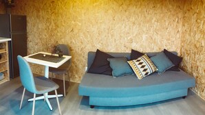 Una habitación con un sofá azul, una mesita y una silla.