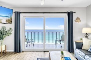 Una habitación con balcón con vistas al océano, un sofá, una lámpara y una planta.
