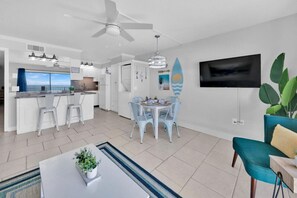 A modern living room with a dining area, a kitchen, and a large window with a view. - BeachFront-Summit 507 (Panama City Beach)