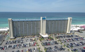 A large hotel with a parking lot in front, a beach, and the ocean in the background. - BeachFront-Summit 507 (Panama City Beach)